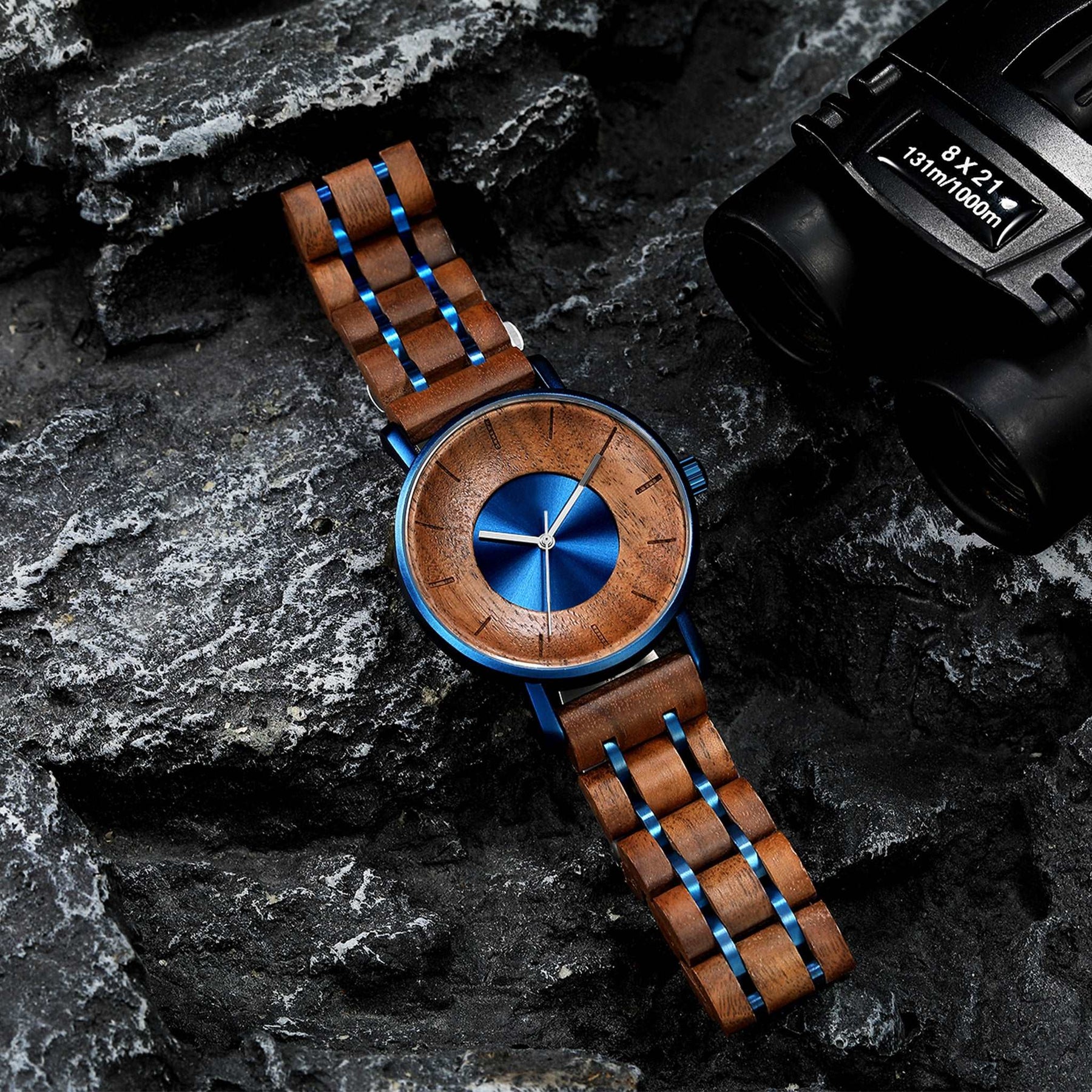 A blue metal case and walnut men watch lying on the black rock