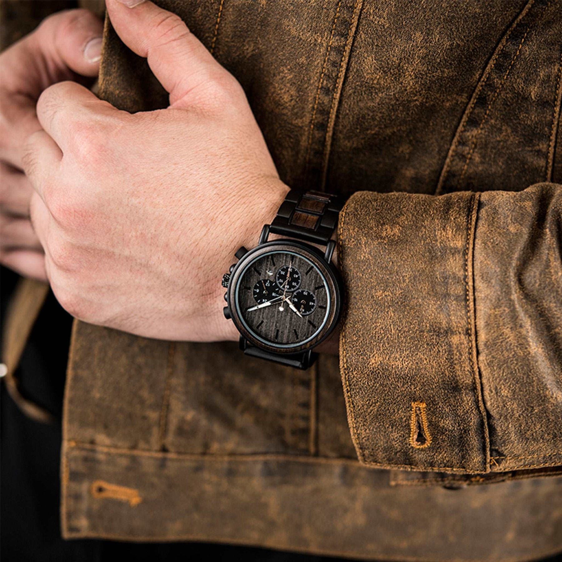 A man wearing a black metal and ebony chronograph watch with black face