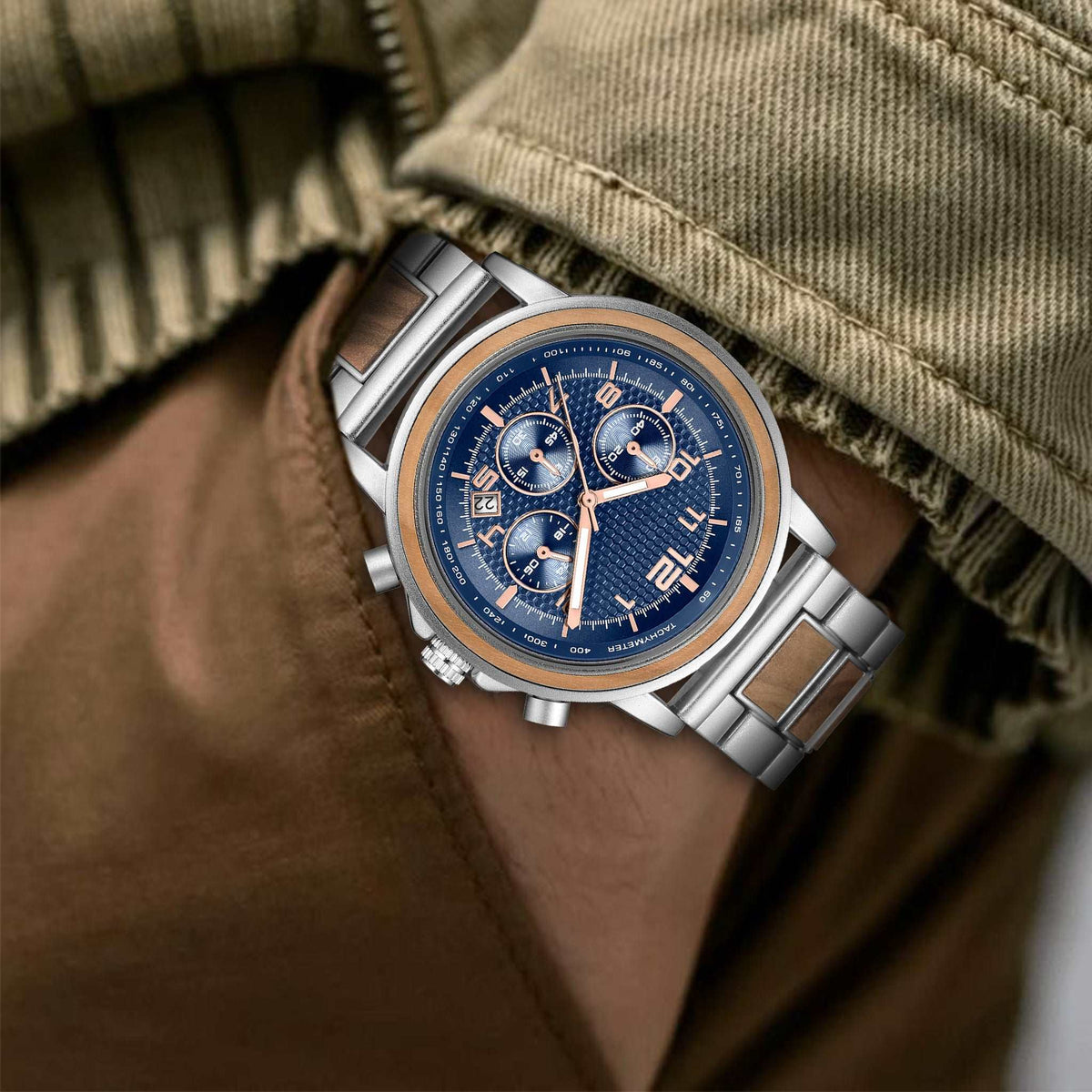 A man wearing a silver and olive wooden watch with blue face