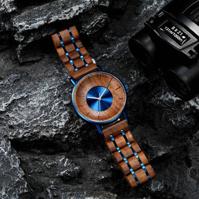 A blue metal case and walnut men watch lying on the black rock